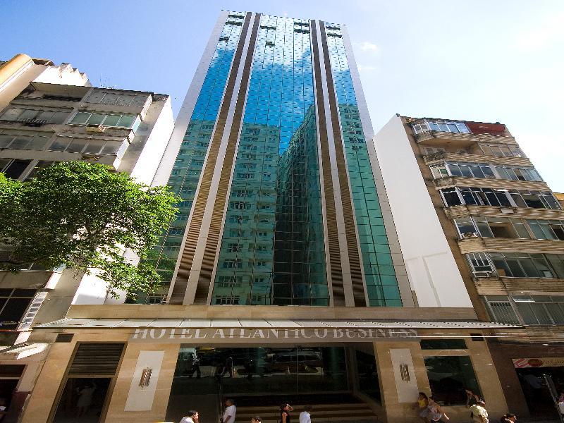 Hotel Atlântico Business Centro Rio de Janeiro Esterno foto The photo shows a modern hotel building, likely a high-rise, with a glass facade that reflects the sky. The hotel appears to have multiple stories, with vertical lines and a sleek design. At the base of the building, there is a sign that reads "Hotel